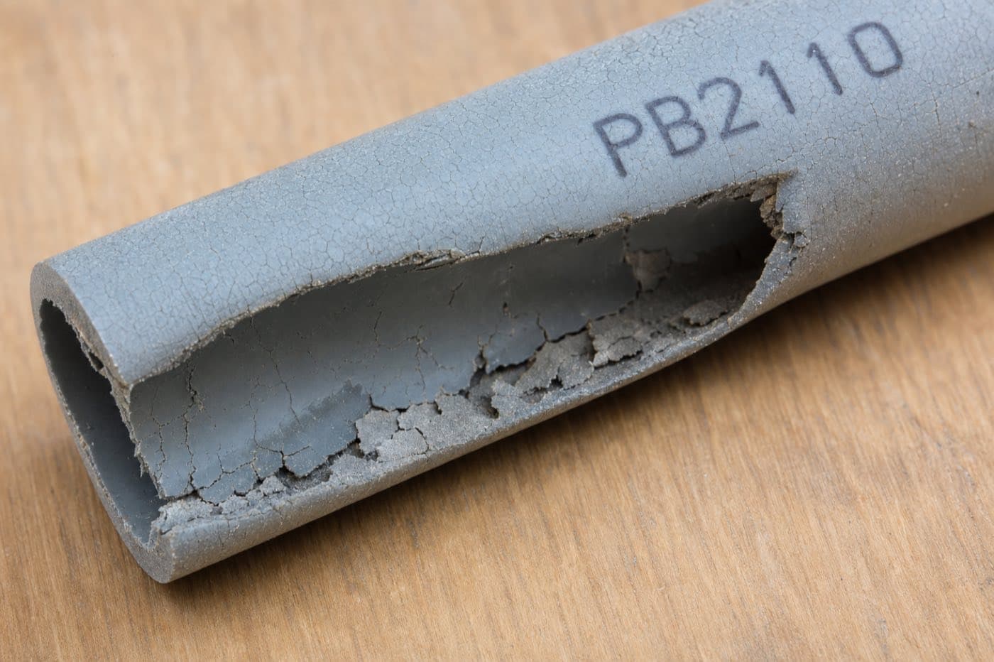 Poly B pipe showing internal cracking and deterioration — PB2110 stamp visible